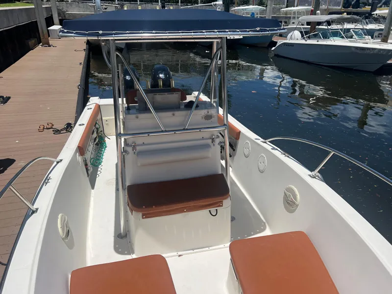 Slide: The Image of 1996 Pursuit 2470 CC boat docked, featuring seating and a T-top. - 25