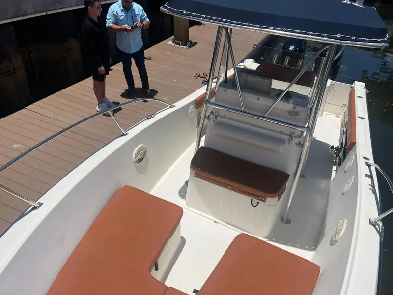 Slide: The Image of 1996 Pursuit 2470 CC boat docked, featuring brown seating and a center console. - 27