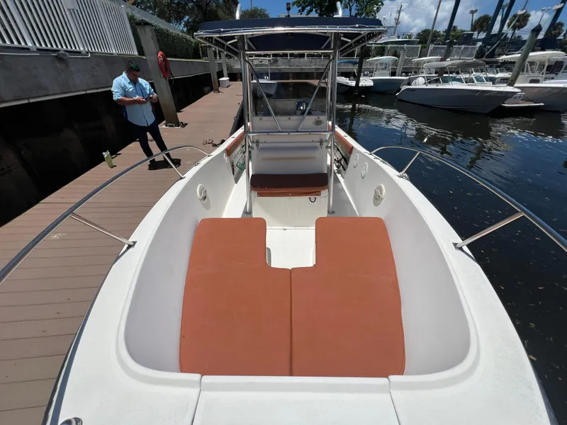 Slide: The Image of 1996 Pursuit 2470 CC boat docked, featuring spacious seating and a center console. - 28