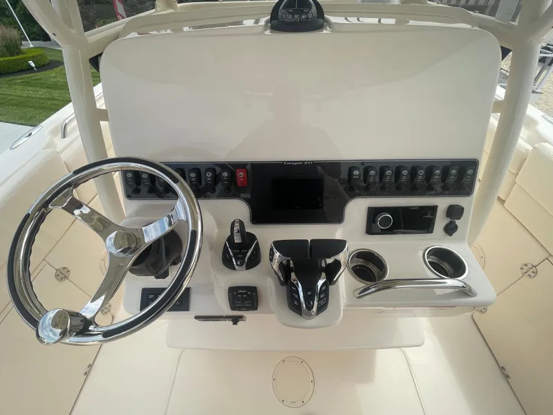 Slide: The Image of 2025 Grady-White Canyon 271 boat dashboard with steering wheel and control panel. - 12