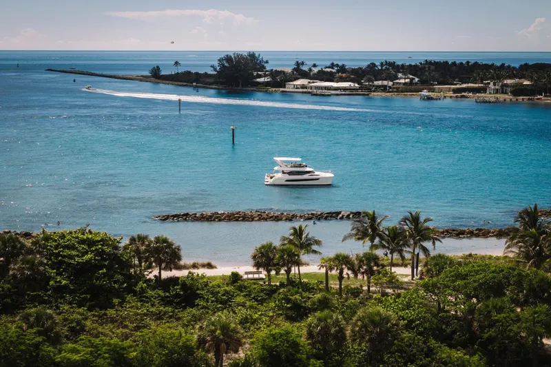 Slide: The Image of 2024 Aquila 44 Yacht cruising in tropical blue waters near a lush green coastline. - 33