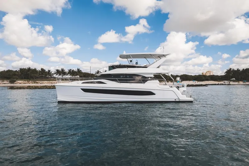 Slide: The Image of 2024 Aquila 44 Yacht cruising on a sunny day with a scenic shoreline backdrop. - 35