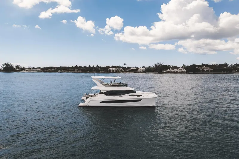 Slide: The Image of 2024 Aquila 44 Yacht cruising on a serene blue waterway under a partly cloudy sky. - 39