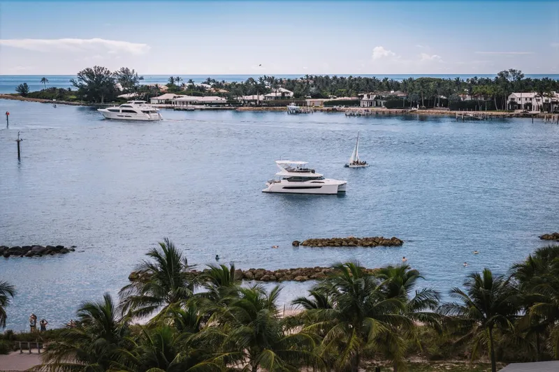Slide: The Image of 2024 Aquila 44 Yacht cruising in a tropical bay with palm trees and other boats. - 40