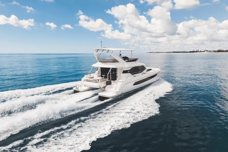 Slide: The Image of 2024 Aquila 44 Yacht cruising on open water under a clear blue sky. - 41