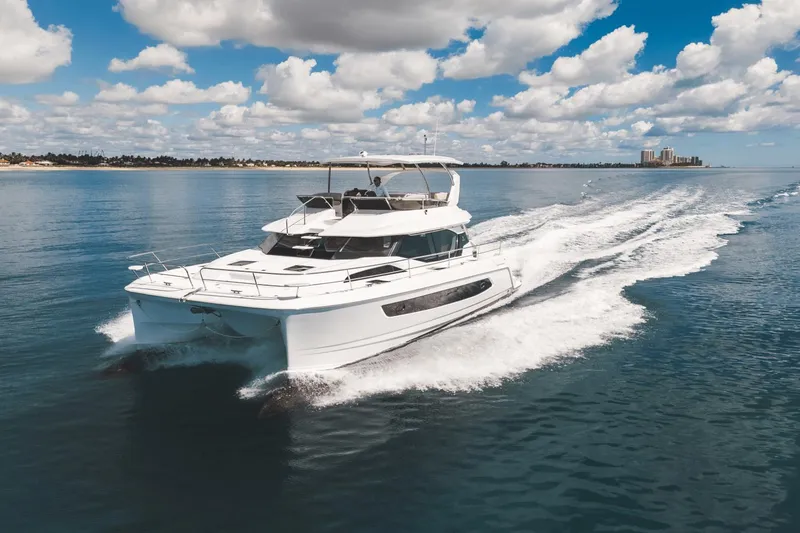 Slide: The Image of 2024 Aquila 44 Yacht cruising on a sunny day with a scenic coastal backdrop. - 44