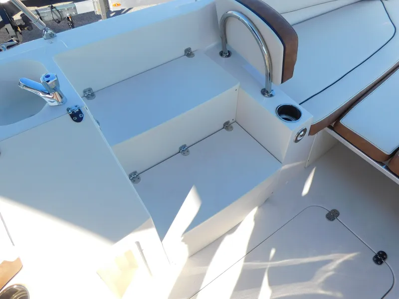 Slide: The Image of 2024 Stingray 212 SC boat interior with seating, steps, and cup holder. - 11