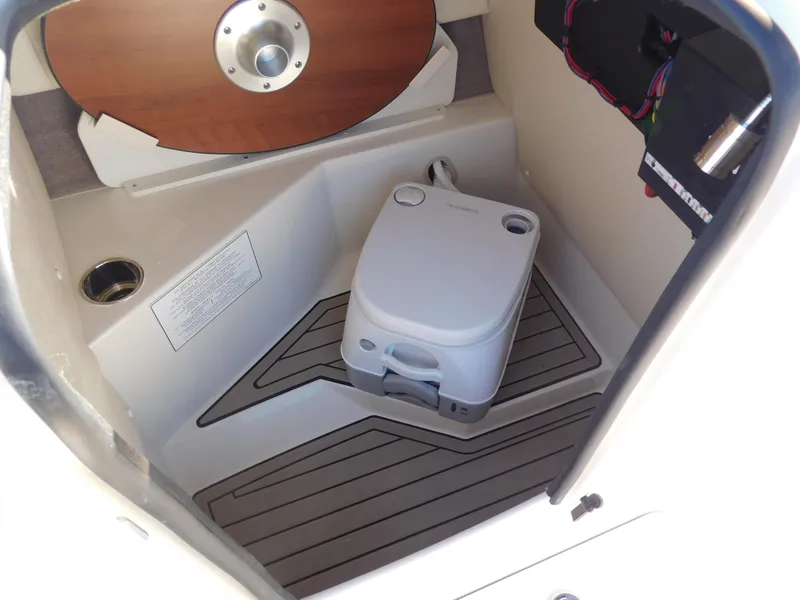 Slide: The Image of 2024 Stingray 212 SC boat interior with portable toilet and storage compartment. - 18