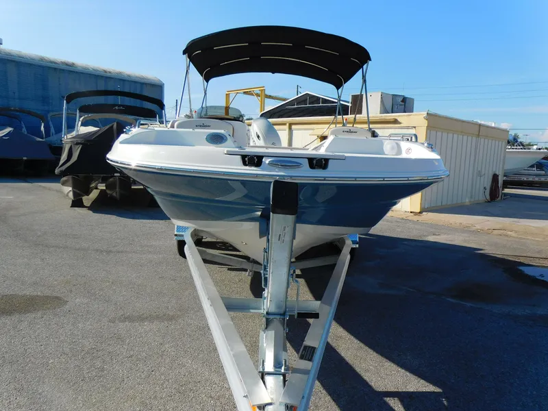 Slide: The Image of 2024 Stingray 212 SC boat on trailer with black canopy in marina. - 3