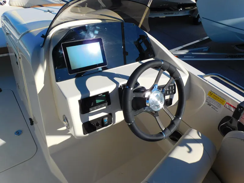 Slide: The Image of 2024 Stingray 212 SC boat dashboard with steering wheel and touchscreen display. - 8