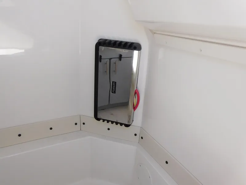 Slide: The Image of 2024 Stingray 253 CC boat interior with a mounted mirror and white walls. - 33