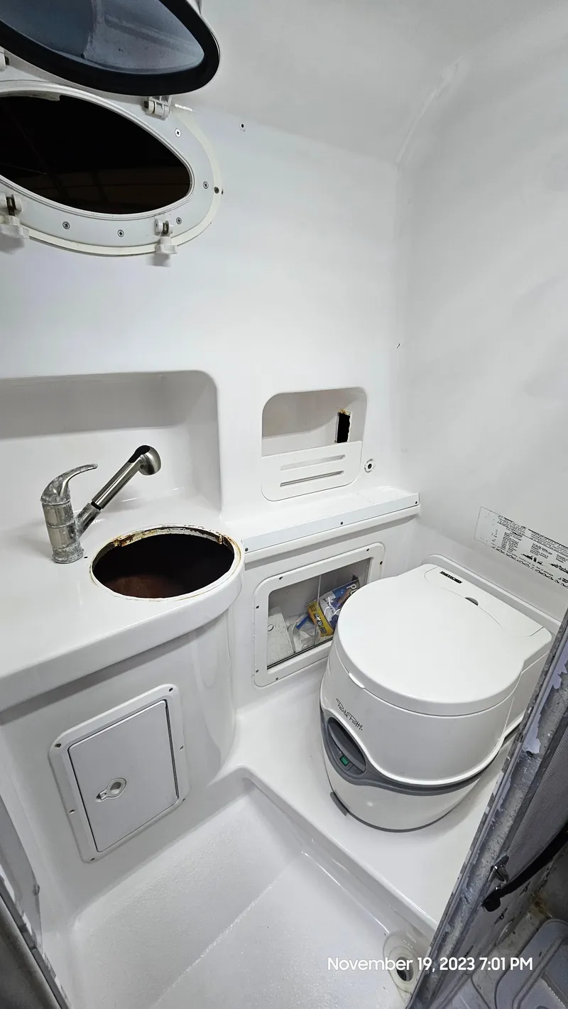 Slide: The Image of 2000 Pro-Line 29 Walkaround boat bathroom with sink, toilet, and storage compartments. - 16