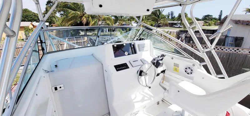 Slide: The Image of 2000 Pro-Line 29 Walkaround boat cockpit with steering wheel and controls, surrounded by clear skies and palm trees. - 2