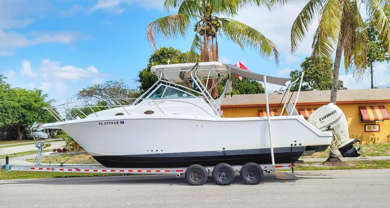 Slide: The Image of 2000 Pro-Line 29 Walkaround boat on trailer, parked near palm trees. - 8