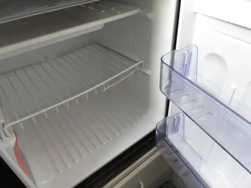 Slide: The Image of Empty refrigerator interior with wire shelf and door compartments on a Stamas 250 Express, 1999 model. - 21