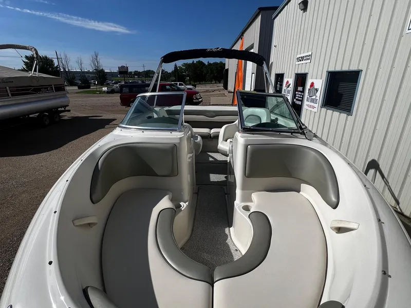 Slide: The Image of 2005 Sea Ray 200 Sport boat with white and gray interior, parked outside a building. - 5