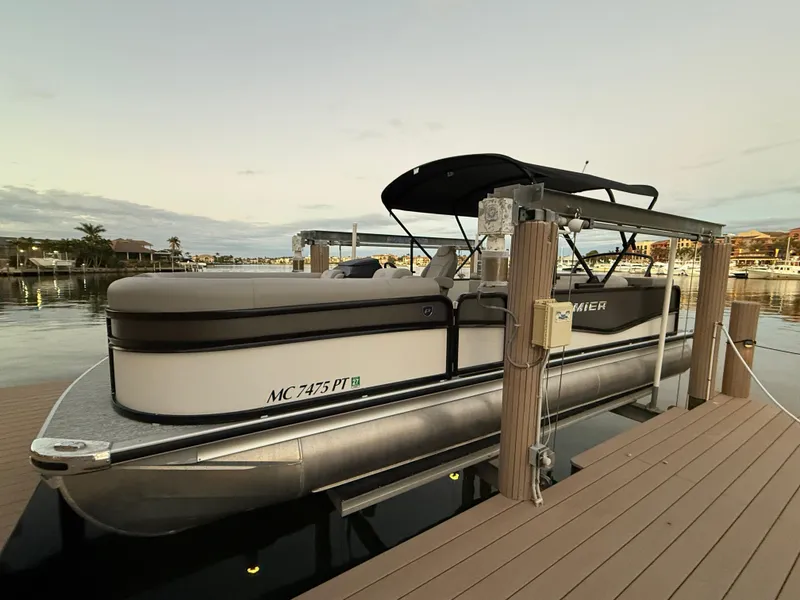 Slide: The Image of 2024 Premier Sunsation 230 RE pontoon boat docked at sunset. - 13