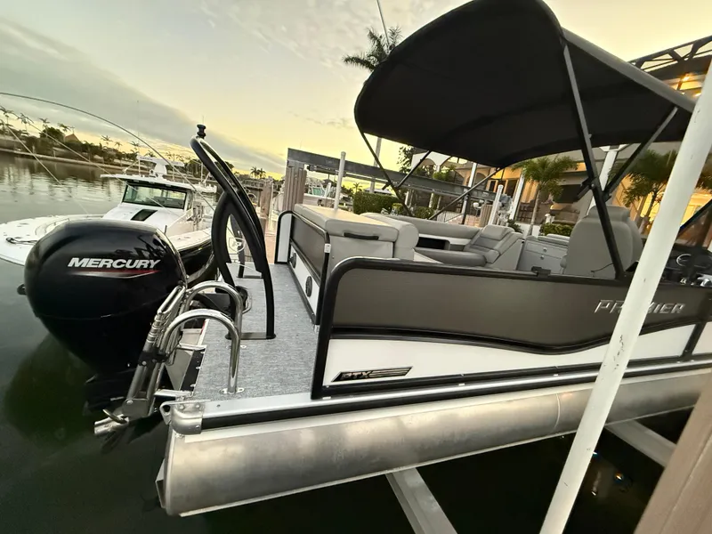 Slide: The Image of 2024 Premier Sunsation 230 RE pontoon boat docked with Mercury engine. - 16
