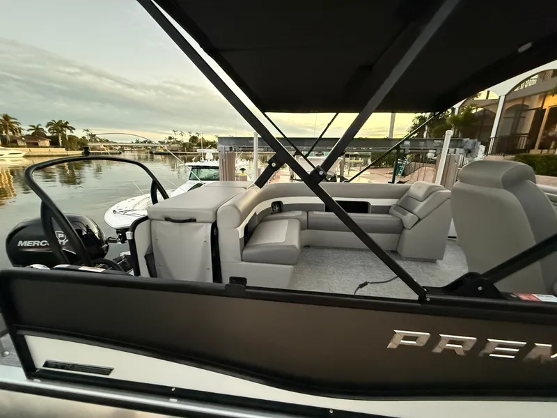 Slide: The Image of 2024 Premier Sunsation 230 RE pontoon boat with spacious seating at a marina. - 17