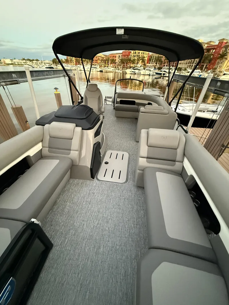 Slide: The Image of 2024 Premier Sunsation 230 RE pontoon boat with spacious seating at a marina. - 18
