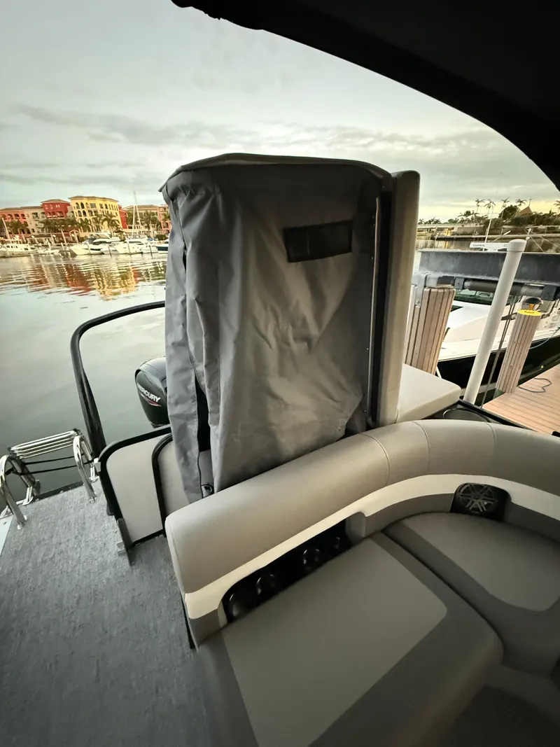 Slide: The Image of 2024 Premier Sunsation 230 RE boat interior with covered seating, docked at marina. - 22