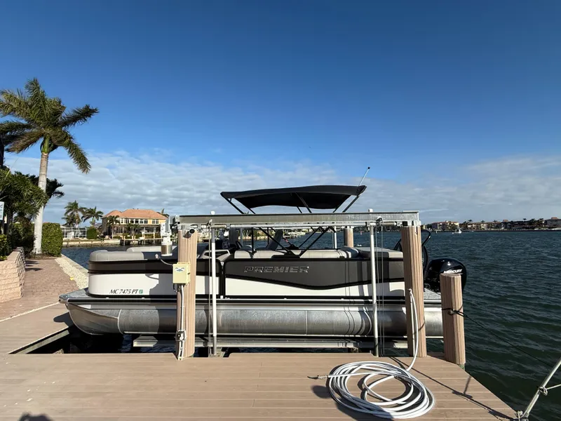 Slide: The Image of 2024 Premier Sunsation 230 RE pontoon boat docked by waterfront. - 24