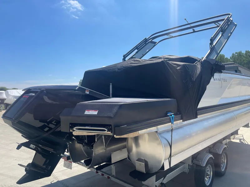 Slide: The Image of 2024 Manitou Cruise pontoon boat on a trailer under a clear blue sky. - 4
