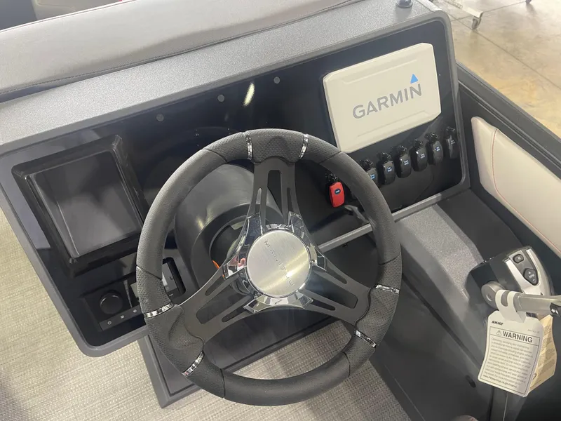Slide: The Image of 2024 Manitou Cruise boat dashboard with Garmin navigation system and steering wheel. - 9