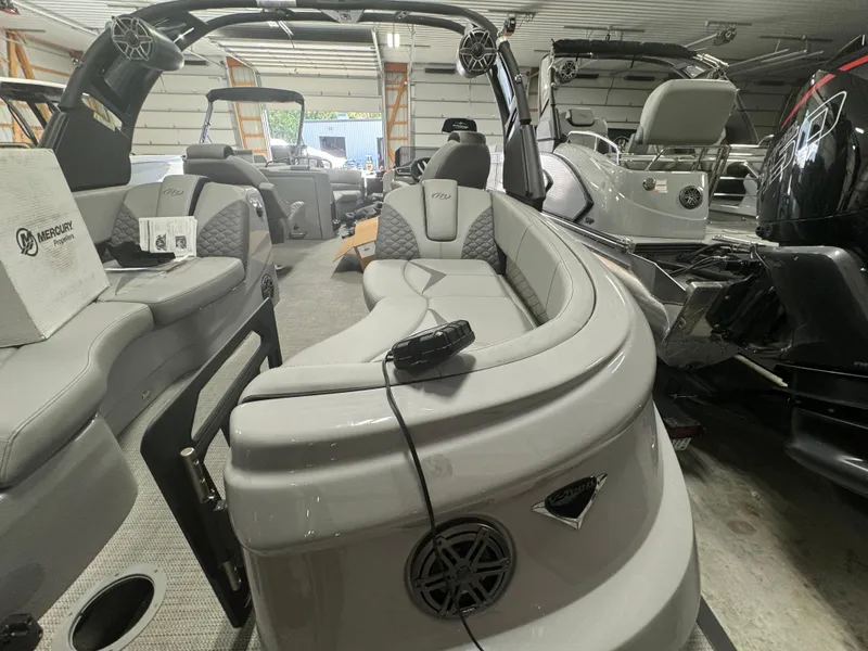 Slide: The Image of 2024 Manitou 25 LX RF pontoon boat interior with luxurious seating in a showroom. - 14
