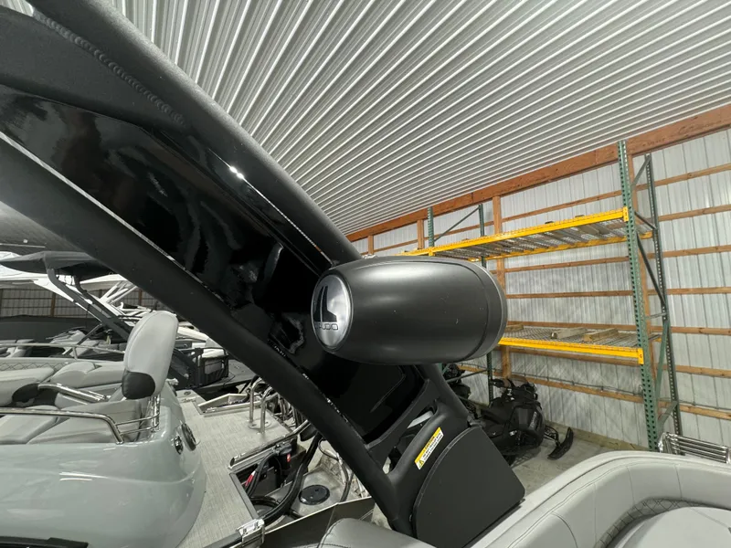 Slide: The Image of 2024 Manitou 25 LX RF boat interior with speaker and seating in a storage facility. - 17