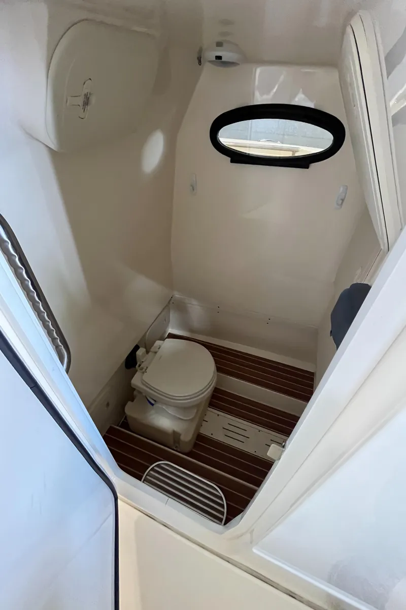 Slide: The Image of 2020 Scout 255 LXF boat interior with compact marine toilet and wooden flooring. - 13