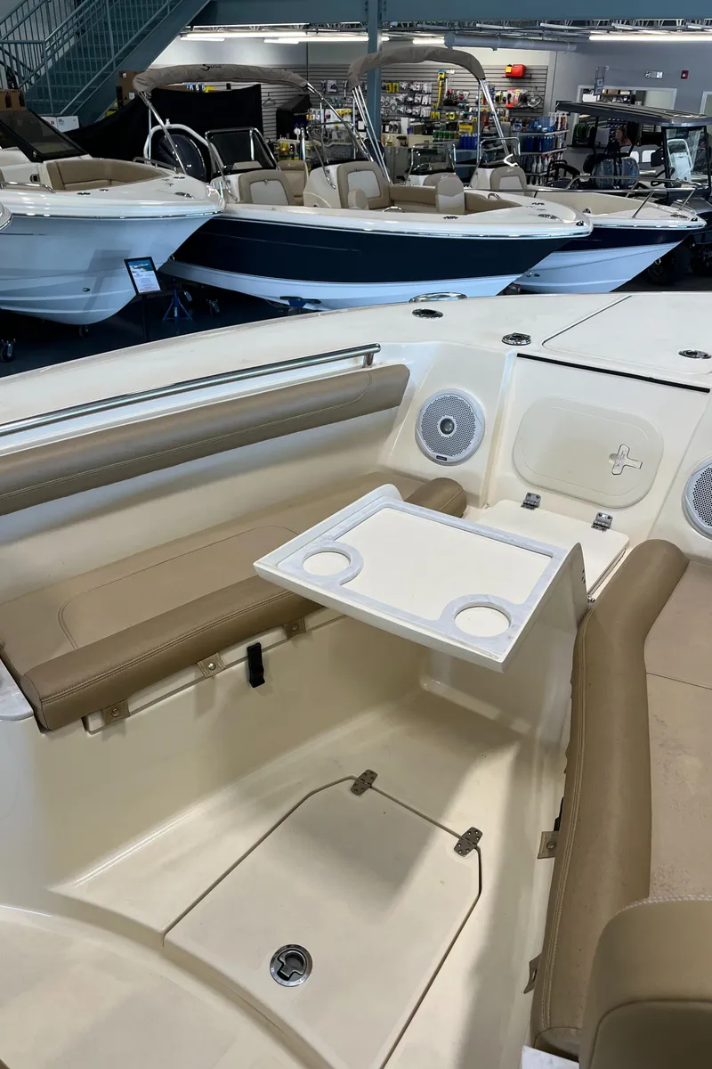 Slide: The Image of 2020 Scout 255 LXF boat interior with seating and table in showroom. - 7