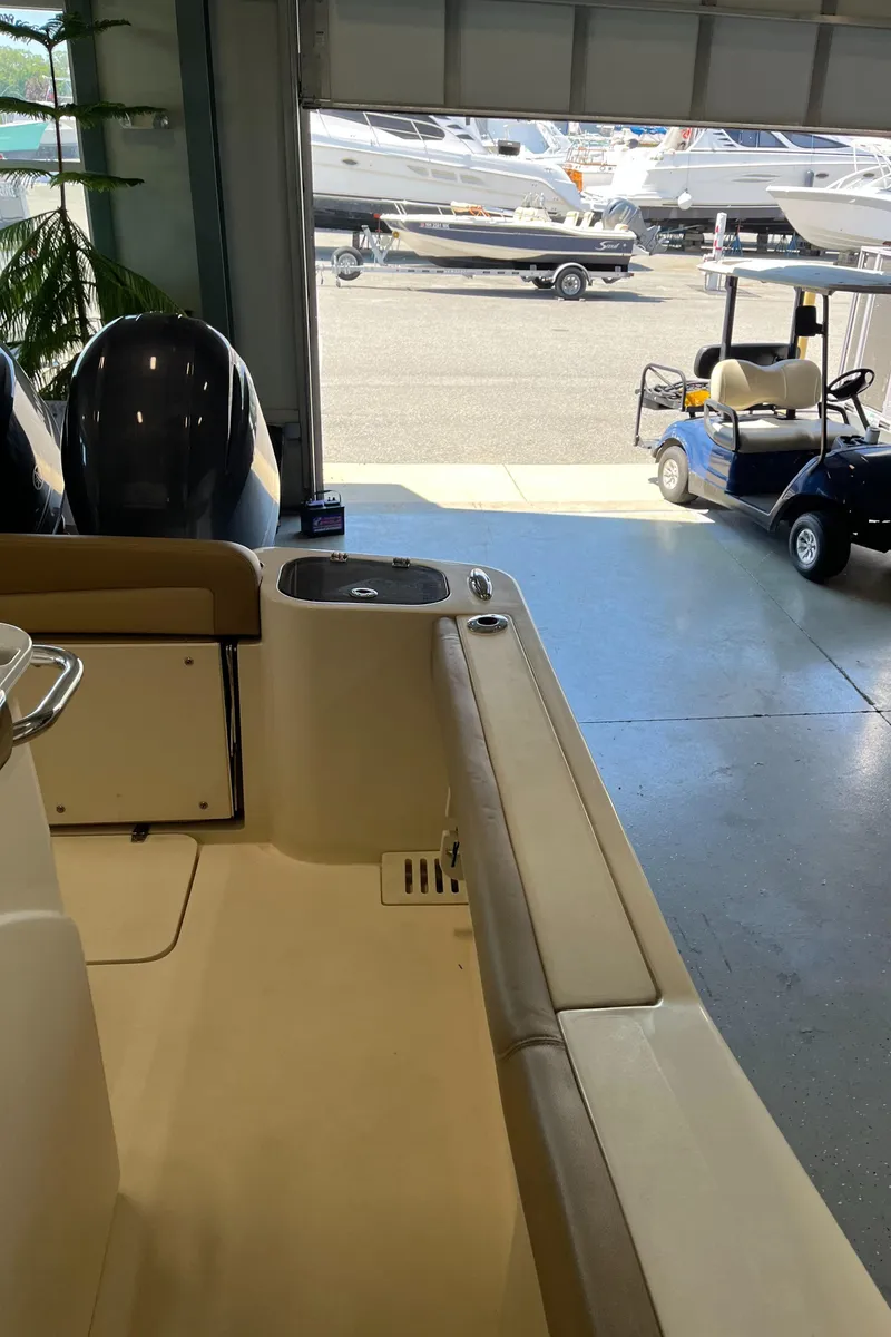 Slide: The Image of 2020 Scout 255 LXF boat interior in showroom with other boats visible outside. - 9