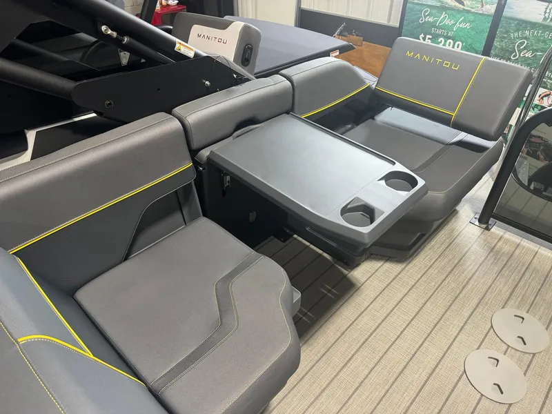 Slide: The Image of 2024 Manitou Explore boat interior with gray seating and table, featuring cup holders. - 11