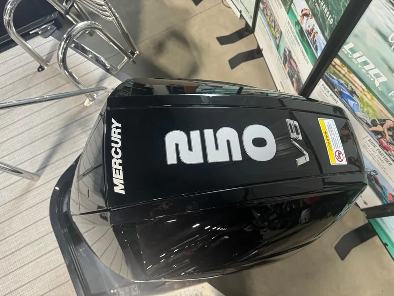 Slide: The Image of 2024 Manitou Explore with Mercury V8 outboard engine displayed indoors. - 14