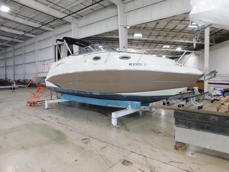 The Image of 2015 Stingray 250 CS boat in a warehouse, elevated on supports. - 1