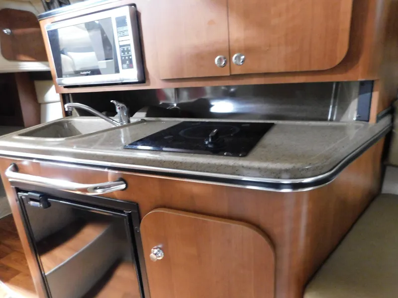 Slide: The Image of 2015 Stingray 250 CS boat kitchen with microwave, sink, and stove. - 12