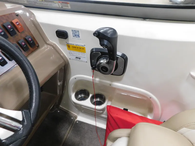 Slide: The Image of 2015 Stingray 250 CS boat cockpit with throttle control and cup holders. - 19