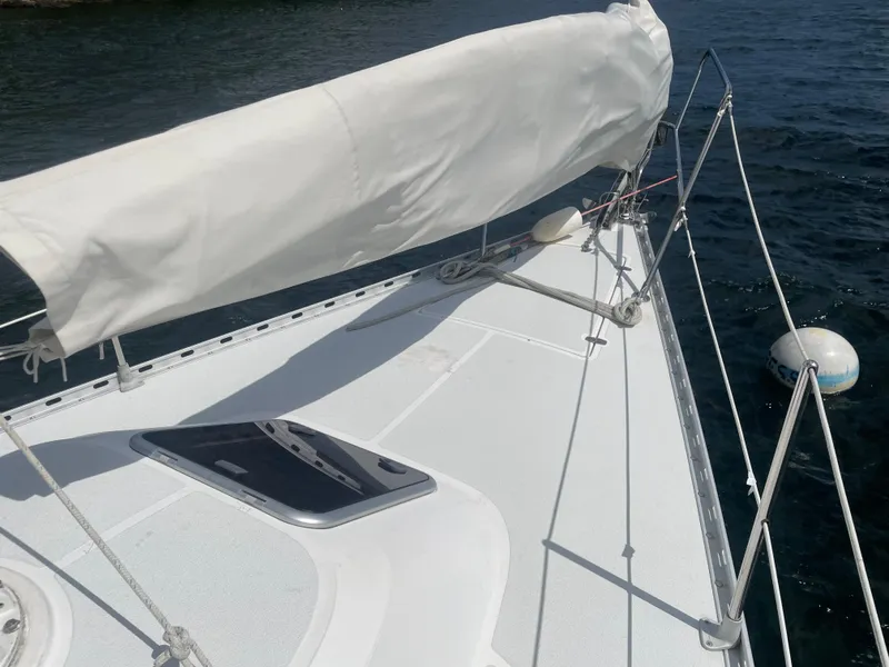 Slide: The Image of Sailboat deck of 1993 Freedom 35 on water, featuring covered sail and hatch. - 14