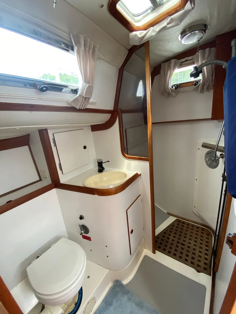 Slide: The Image of 1993 Freedom 35 yacht bathroom with sink, toilet, and shower, featuring wood accents and natural light. - 22