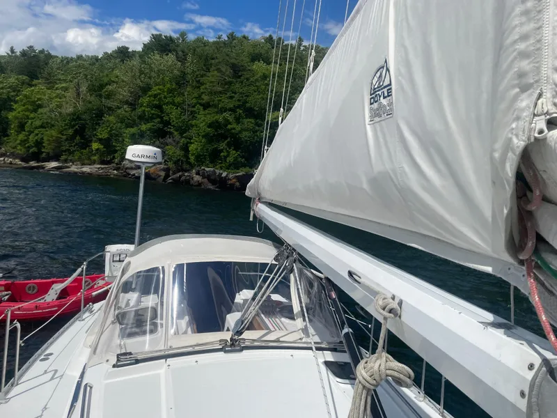 Slide: The Image of Sailboat Freedom 35, 1993 model, with white sails docked near lush green shoreline. - 31