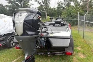 Slide: The Image of 2024 Skeeter ZX200 boat with powerful outboard motor, parked on grass near a fence. - 8