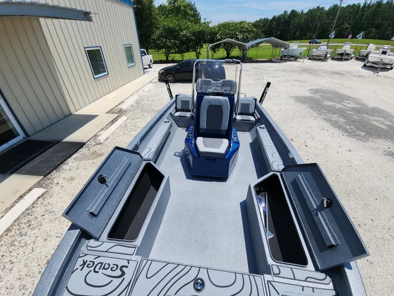 Slide: The Image of 2025 Xpress H20B boat with open storage compartments, parked outdoors. - 11
