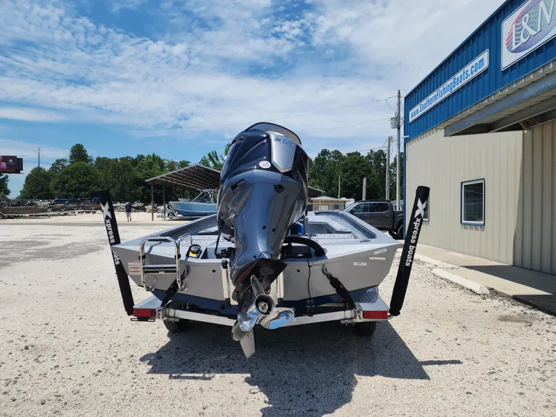 Slide: The Image of 2025 Xpress H20B boat with outboard motor, parked outside a building on a sunny day. - 5