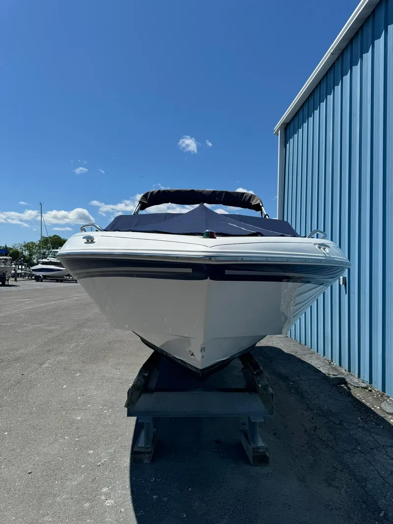 Slide: The Image of 2004 Four Winns 200 Horizon boat on trailer, parked beside blue building under clear sky. - 4