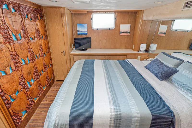 Slide: The Image of 1996 Hatteras 70 Sport Deck Motor Yacht bedroom with striped bedding and turtle-themed wall art. - 29