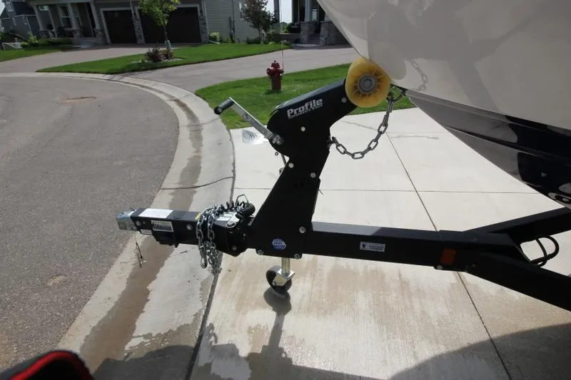Slide: The Image of 2019 Yamaha Boats 212 Limited S trailer hitch and bow roller on a driveway. - 8