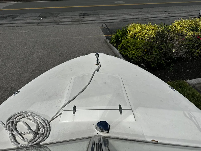 Slide: The Image of 1967 Bertram 20 Moppie boat bow with rope, docked near a road and garden. - 8