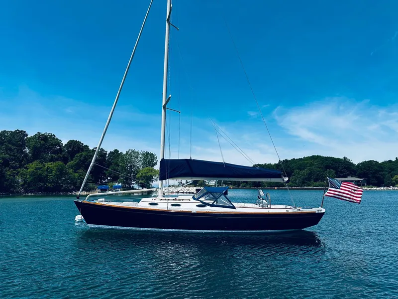 Slide: The Image of 2009 Alerion Express 38 sailboat on calm water with American flag, clear sky background. - 10