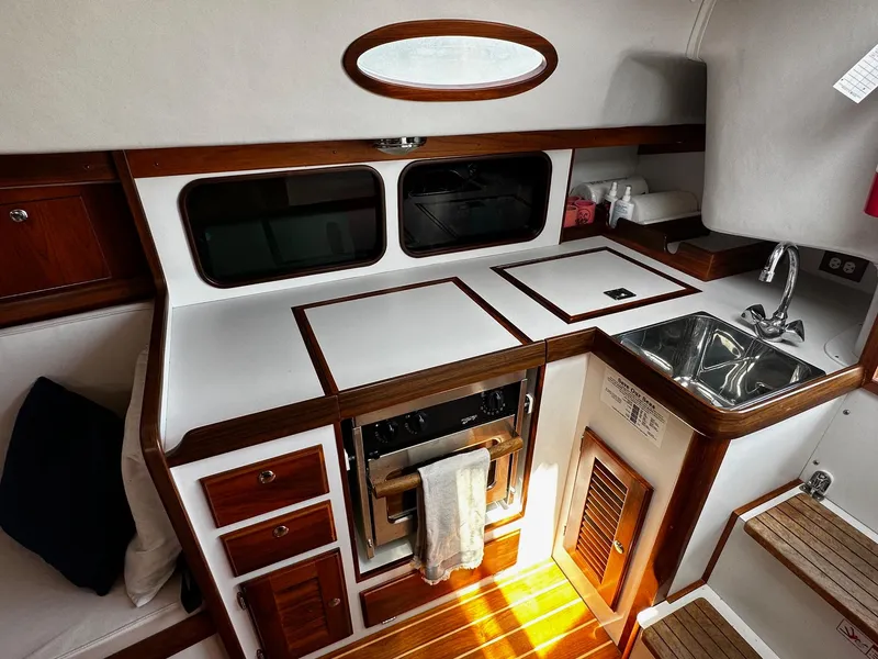 Slide: The Image of Interior of 2009 Alerion Express 38 sailboat, featuring a compact kitchen with wood accents. - 21